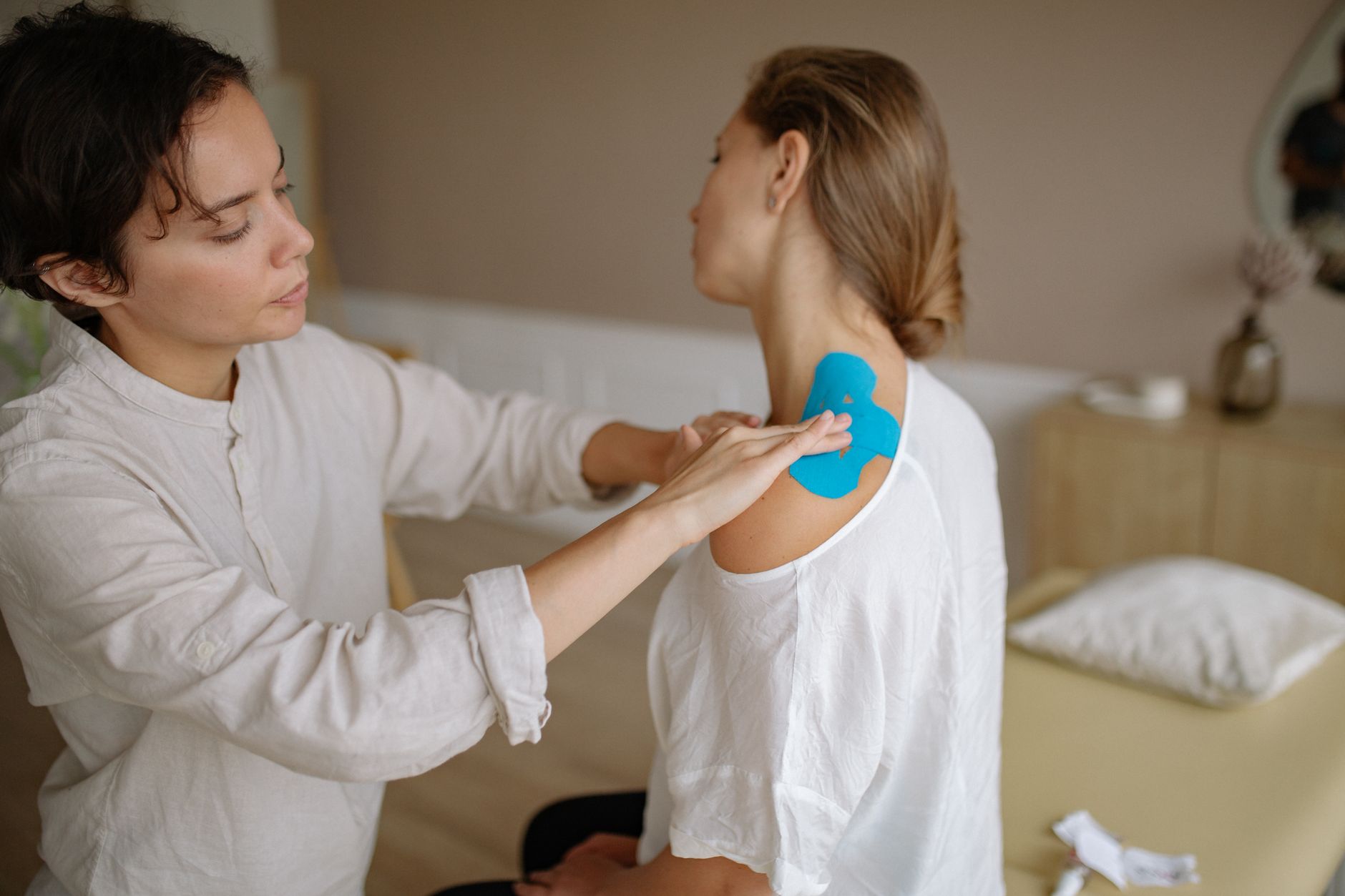 Physiotherapist applying kinesiology tape to a client's shoulder